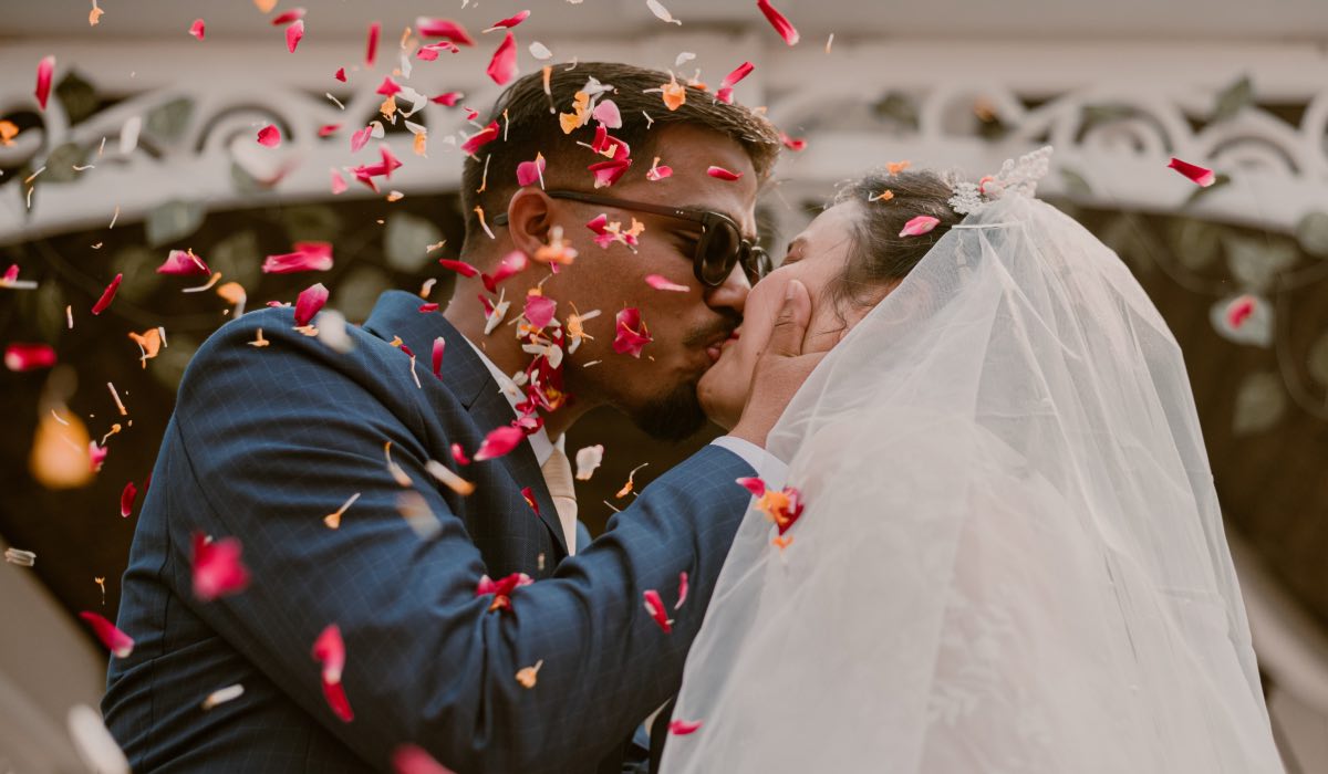 wedding couple sharing a kiss while confettii falls down