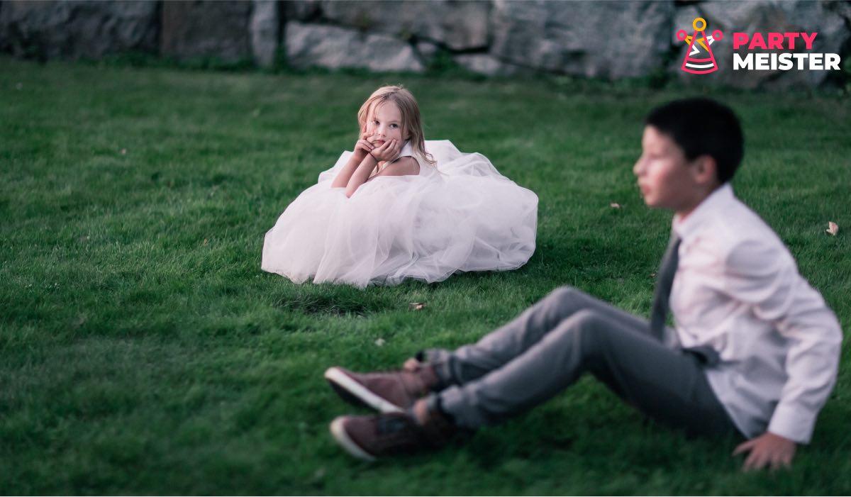 A girl and a boy dressed smartly, sitting on grass