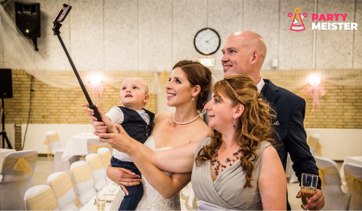 Bride, two guests and a toddler taking a photo with a selfie stick