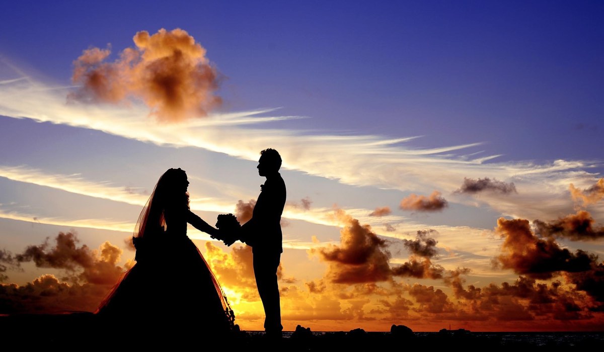 silhouettes of a wedding couple standing against a sunset