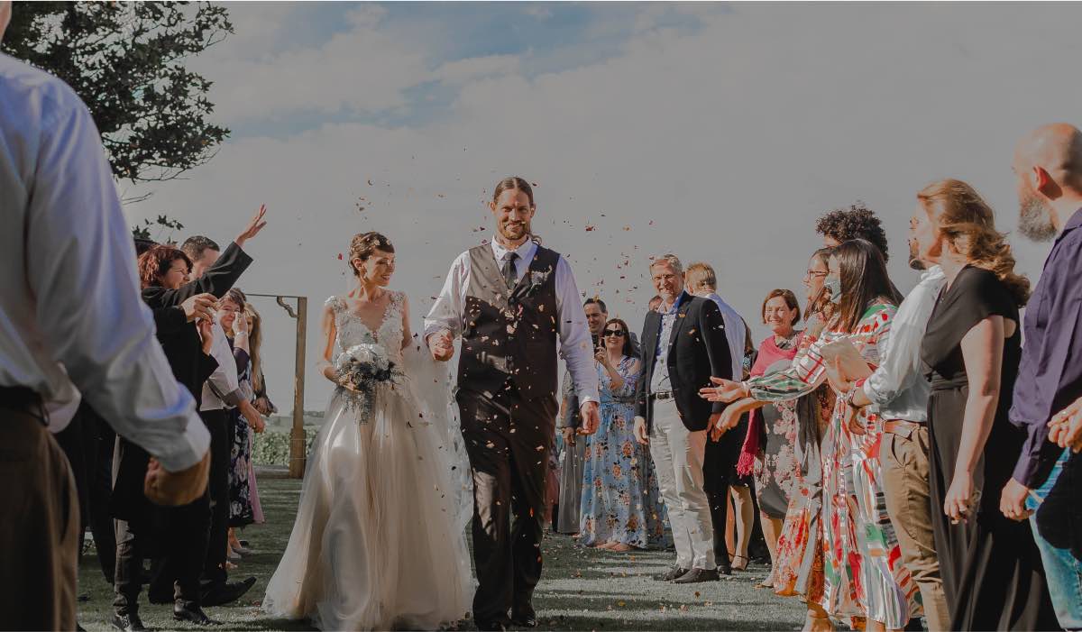 wedding couple walking surrounded by guests with confetti sprinkling