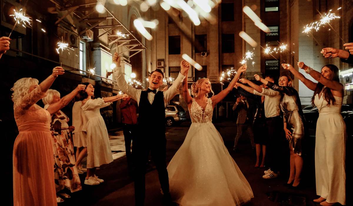wedding couple surrounded by guests holding fireworks