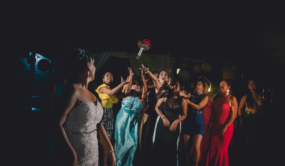 wedding guests catching a bouquet in a darkened room