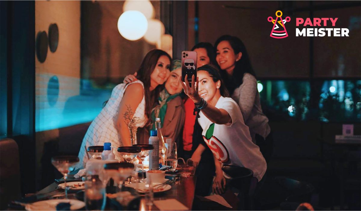 A group of women at the top of a table, taking a selfie